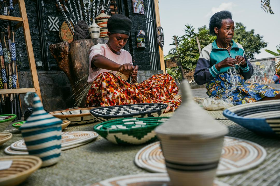Two artisans weaving traditional Rwandan baskets by hand.