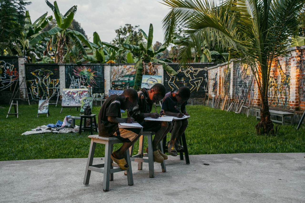 An open-air art class on the VAC lawn, surrounded by community murals.