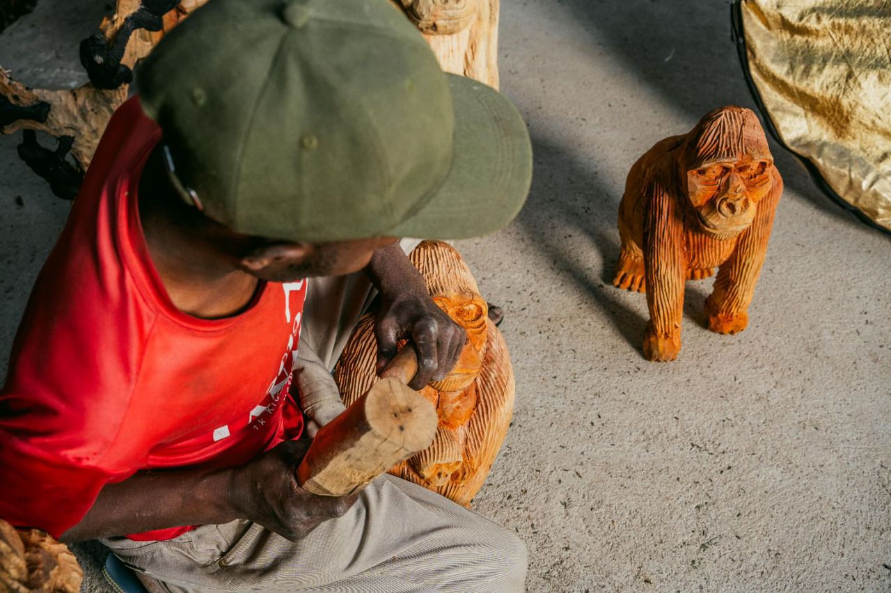 A resident carver shapes a gorilla sculpture from raw lava-stone at Volcano Arts Center.